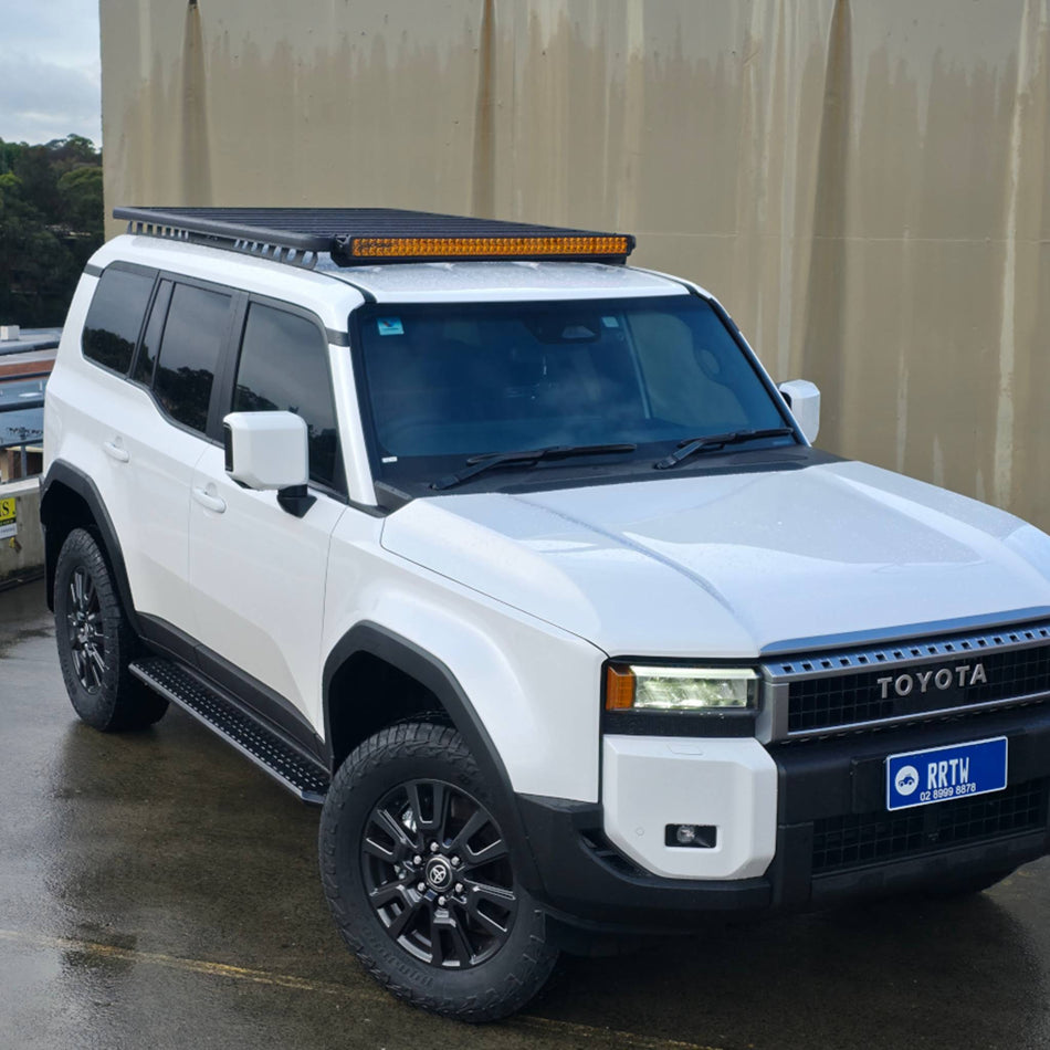 White Toyota SUV with additional lights on a wet road