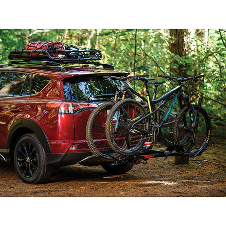 Red SUV with two bikes on the rack in the woods