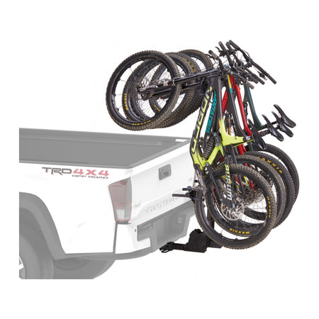 Four mountain bikes hanging behind a white ute