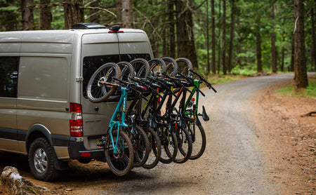 Van loaded with six MTBs on a forest track
