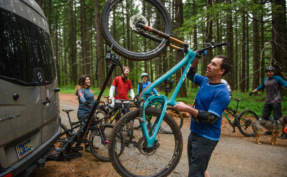 Rider lifting a mountain bike onto the vertical rack
